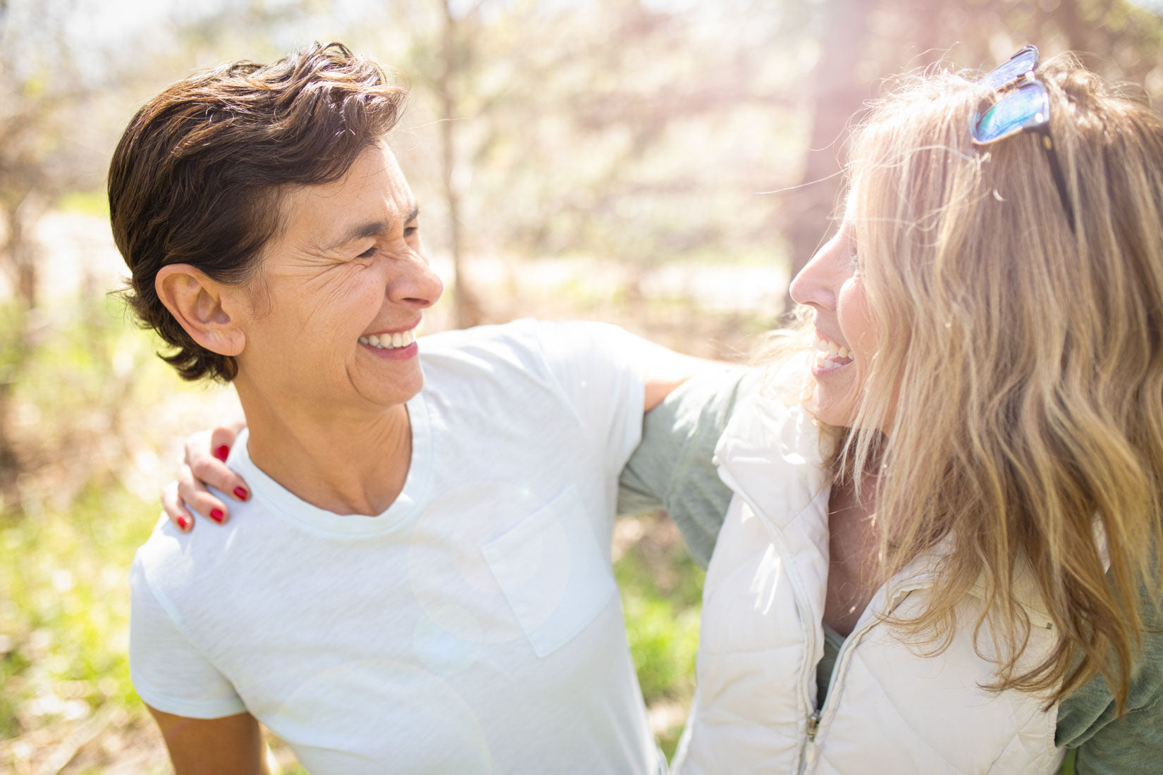 Two attractive older women with their arms around each other smiling